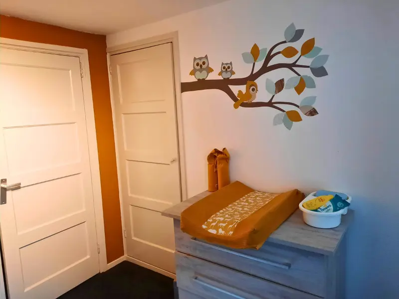 Okergele babykamer met uilentak in groen en oker.